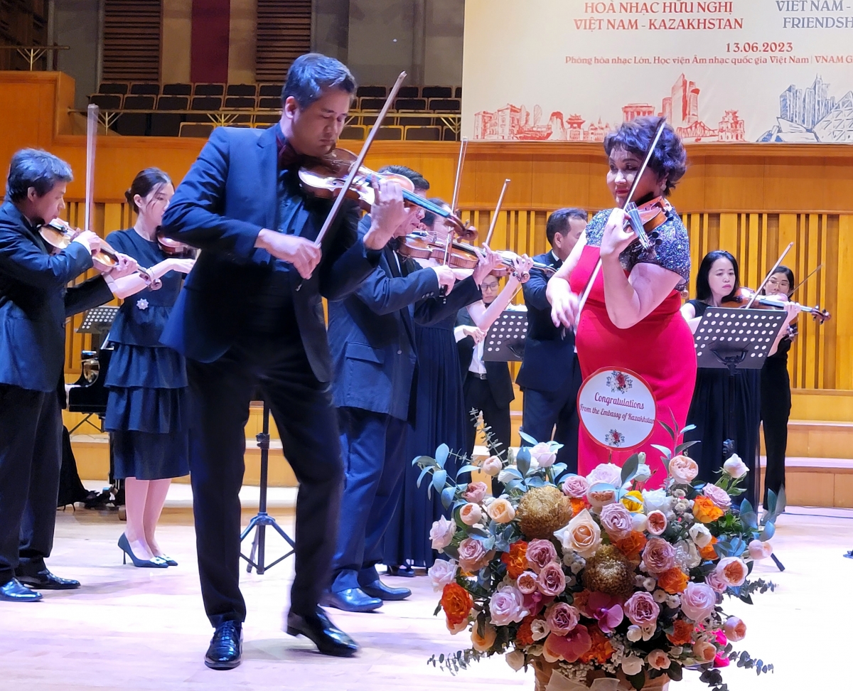 GS-NSND đàn violin Mussakhajaeva Aiman và NSUT đàn violin Bùi Công Duy cùng Dàn nhạc thính phòng Hà Nội biểu diễn trên sân khấu.